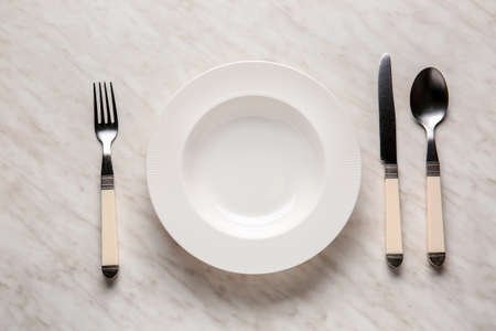 Empty plate and cutlery on light backgroundの写真素材