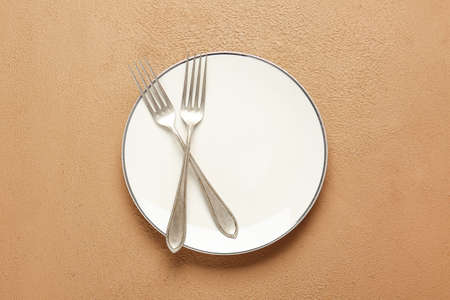 Empty plate and cutlery on color backgroundの写真素材