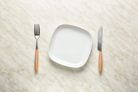 Empty plate and cutlery on light backgroundの写真素材
