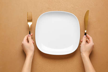 Woman with empty plate and cutlery at tableの写真素材