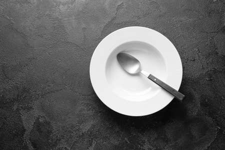 Empty plate and spoon on dark backgroundの写真素材