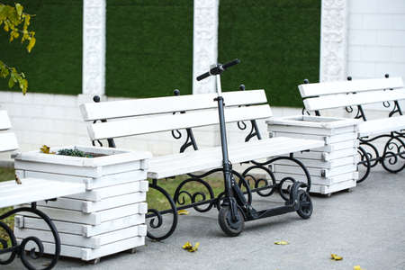 Modern electric kick scooter near bench outdoorsの写真素材