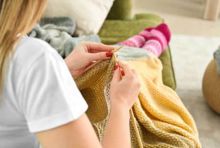 Young woman knitting warm plaid at homeの写真素材