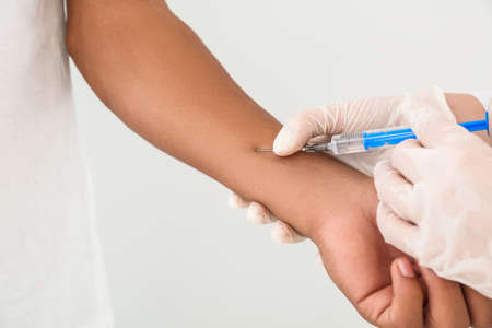 Female doctor conducting Mantoux test against light backgroundの写真素材