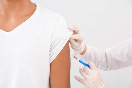 Doctor vaccinating teenage boy on white background, closeupの写真素材