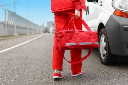 Female paramedic with bag near ambulance car outdoors