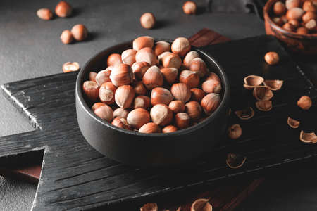Bowl with tasty hazelnuts on dark backgroundの写真素材