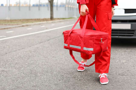 Female paramedic with bag near ambulance car outdoorsの写真素材