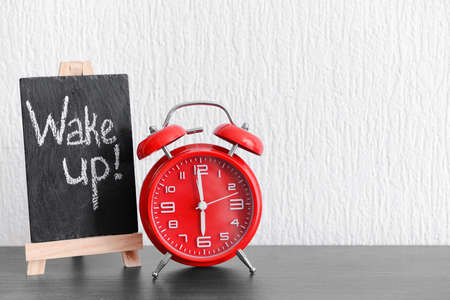 Alarm clock and chalkboard with text WAKE UP on tableの写真素材