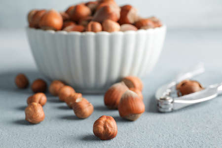 Bowl with tasty hazelnuts and cracker on color backgroundの写真素材