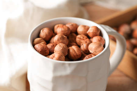 Mug with tasty hazelnuts on table, closeupの写真素材