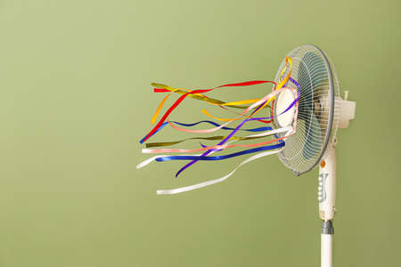 Electric fan with fluttering ribbons on color backgroundの写真素材