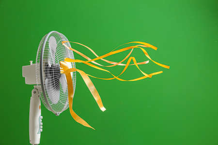 Electric fan with fluttering ribbons on color backgroundの写真素材