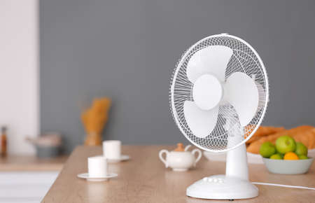 Electric fan on table in kitchenの写真素材