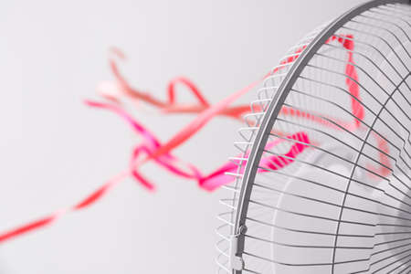 Electric fan with fluttering ribbons on light backgroundの写真素材