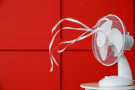 Electric fan with fluttering ribbons near color wallの写真素材