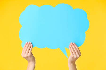 Female hands with blank speech bubble on color backgroundの写真素材