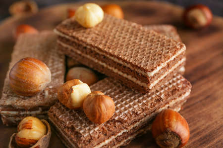 Tasty chocolate waffles with hazelnuts on wooden board, closeupの写真素材