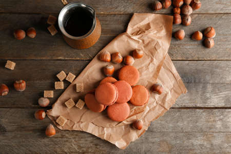 Tasty macarons with hazelnuts and coffee on table