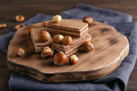 Tasty chocolate waffles with hazelnuts on wooden boardの写真素材