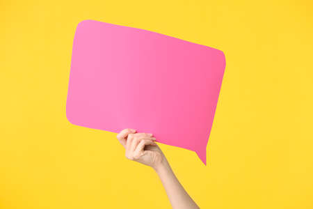 Female hand with blank speech bubble on color backgroundの写真素材