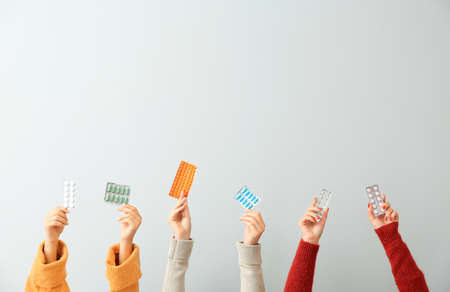 Female hands with different medicines on light backgroundの写真素材