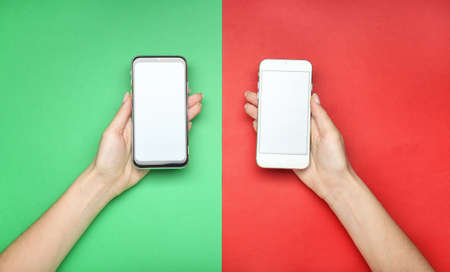 Female hands with modern mobile phones on color backgroundの写真素材