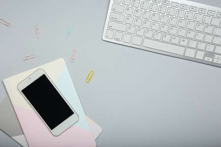 Mobile phone, PC keyboard and notebooks on light backgroundの写真素材