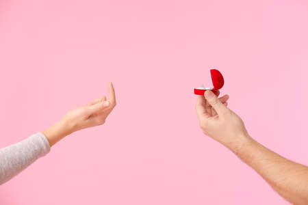 Hand of young man proposing to his girlfriend on color backgroundの写真素材