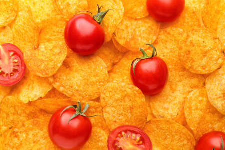 Tasty potato chips with tomatoes as backgroundの写真素材