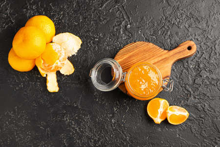 Jar of jam and tasty tangerines on dark backgroundの写真素材