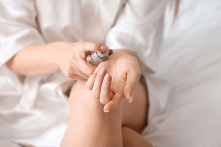 Young woman applying cosmetic serum on her skin at home, closeupの写真素材