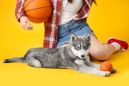 Stylish woman with funny husky puppy and balls on color background