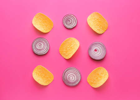 Tasty potato chips and onion on color backgroundの写真素材