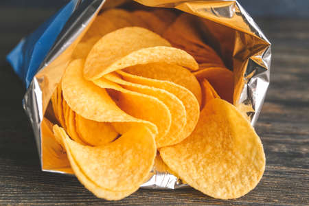 Open pack with tasty potato chips on tableの写真素材