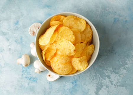 Bowl with tasty potato chips and mushrooms on tableの写真素材