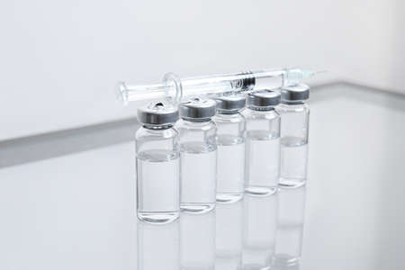 Syringe with filler for cosmetology and ampules on table