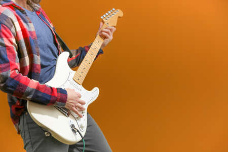 Young man playing guitar on color background