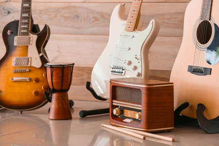 Modern guitars, drum and radio receiver near wooden wallの写真素材