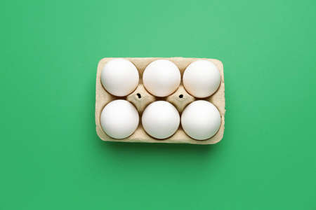 Box with fresh raw eggs on color background