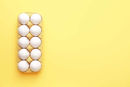 Box with fresh raw eggs on color background