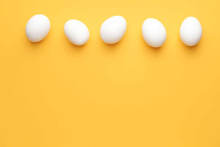 Fresh raw eggs on color backgroundの写真素材