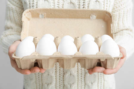 Woman with box of fresh raw eggs, closeup