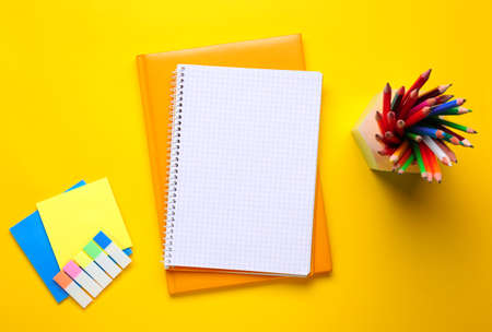 Empty notebooks with stationery on color background
