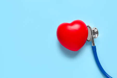 Modern stethoscope and red heart on color backgroundの写真素材
