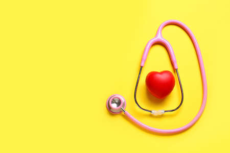 Modern stethoscope and red heart on color background