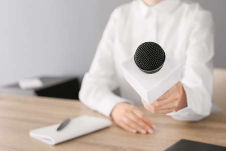 Female journalist with microphone having an interview in office, closeupの写真素材