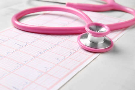 Stethoscope and cardiogram on wooden background, closeup