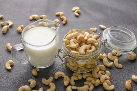 Jug of cashew milk and nuts on dark backgroundの写真素材