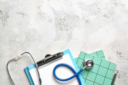 Stethoscope, clipboard and notebooks on tableの写真素材